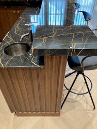 a kitchen with black marble counter tops and stools