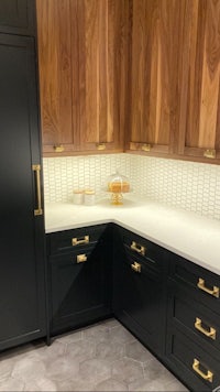 a kitchen with black cabinets and gold hardware